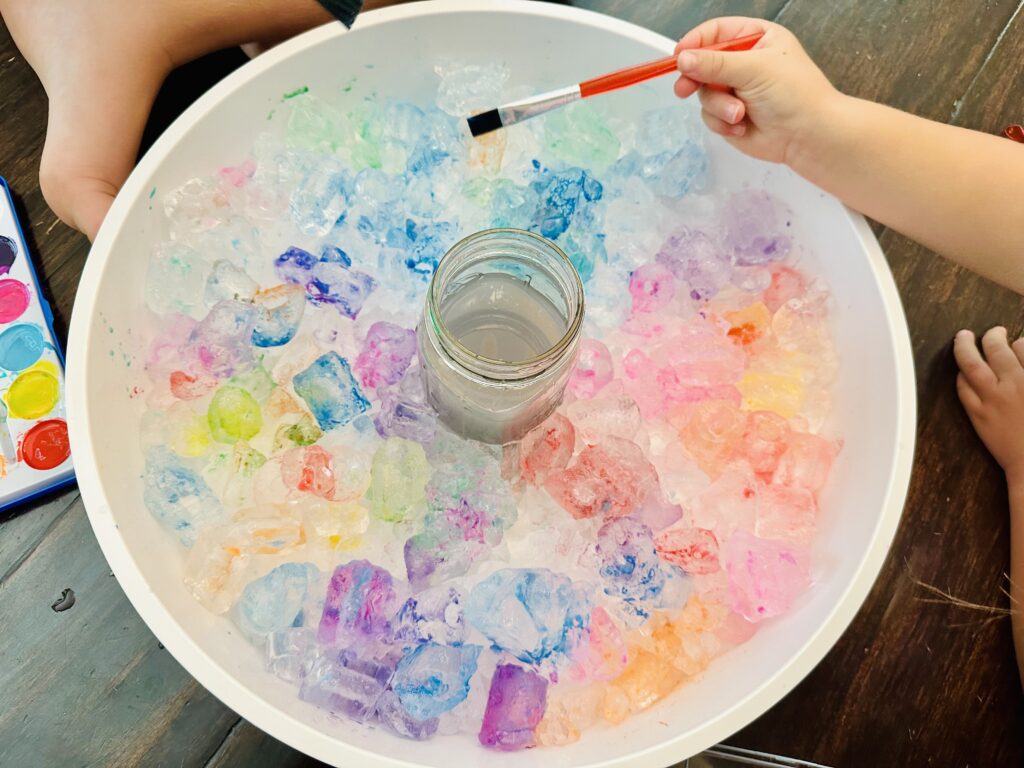 Girl painting ice cubes with watercolors.