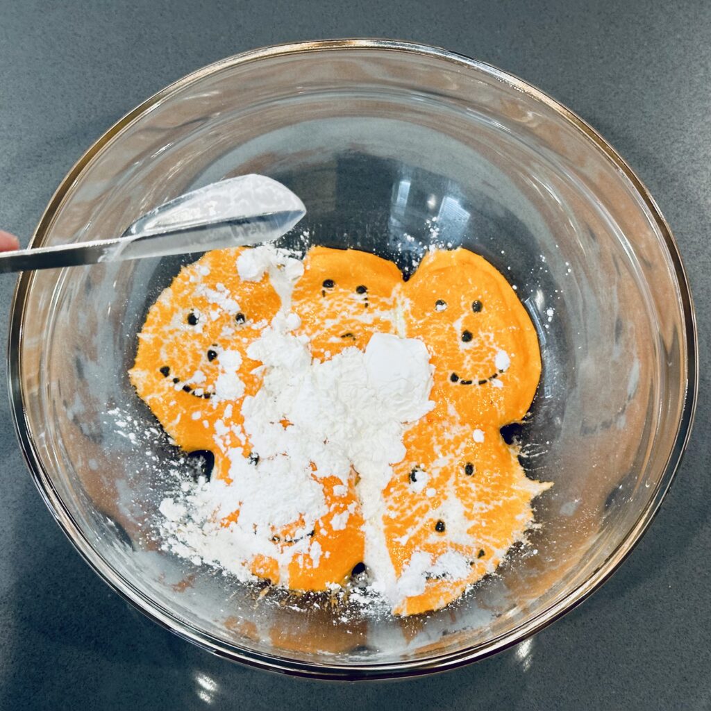 Adding corn starch to pumpkin peeps in a mixing bowl