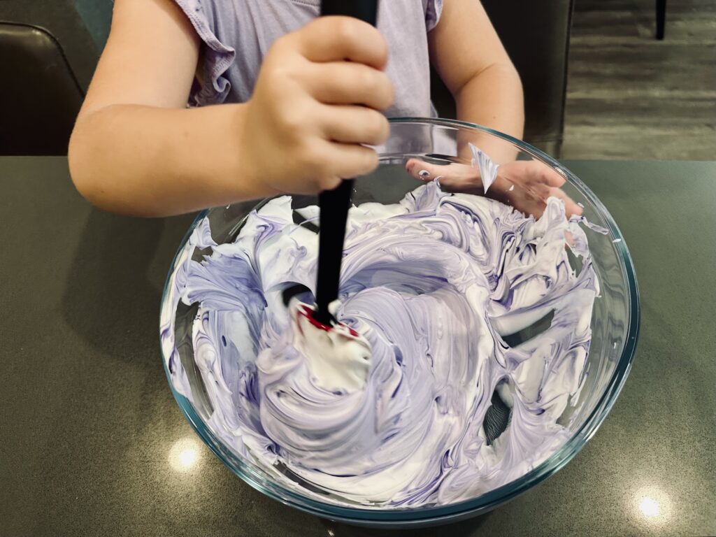 Purple food coloring added to the shaving cream ina mixing bowl.