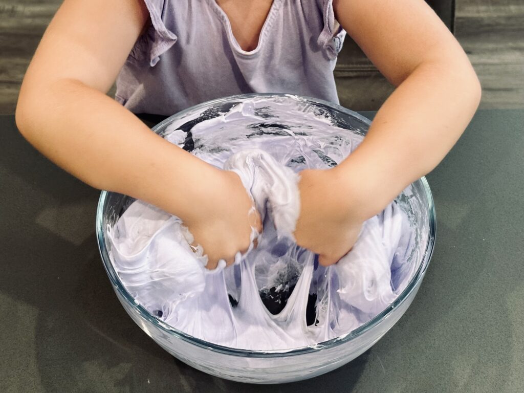 Kneading the fluffy slime ingedients together in a mixing bowl.