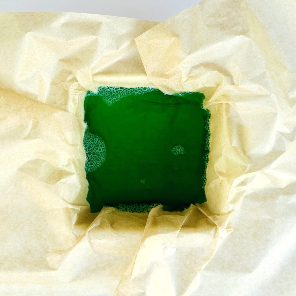 Gelatin mixture in a parchment paper lined baking dish.