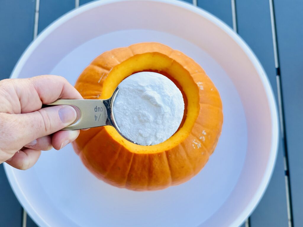 Adding baking soda, soap, and food coloring in the pumpkin volcano.