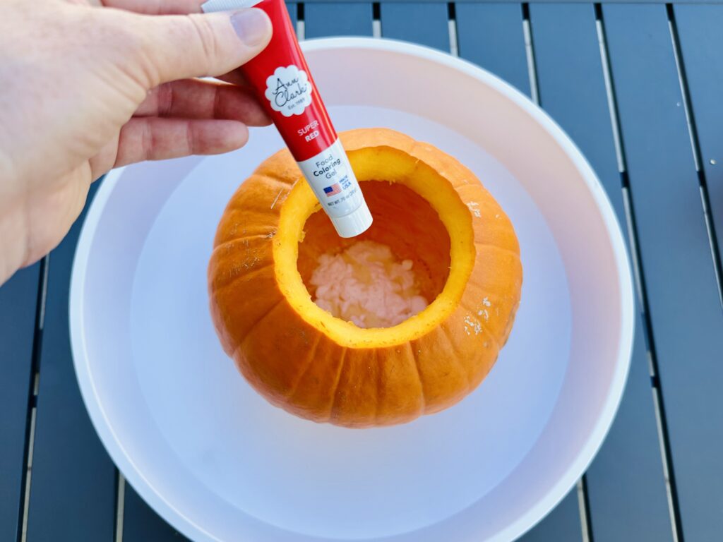 Adding baking soda, soap, and food coloring in the pumpkin volcano.