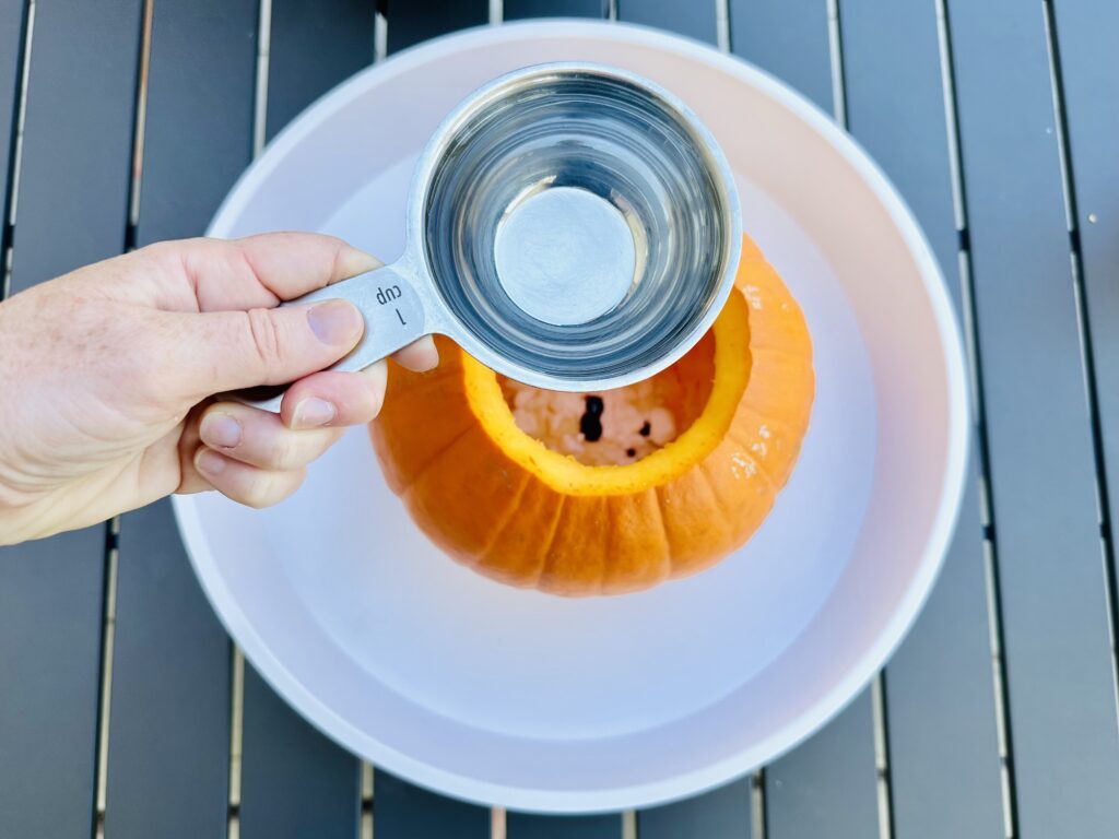 Mixing vinegar with the baking soda, soap, and food coloring in the pumpkin.