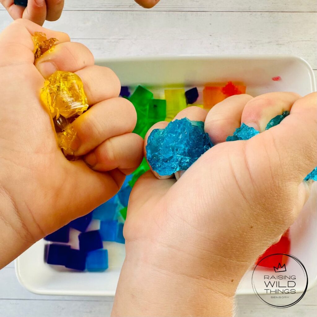 Kid's hands squeezing and squishing the jello blocks.