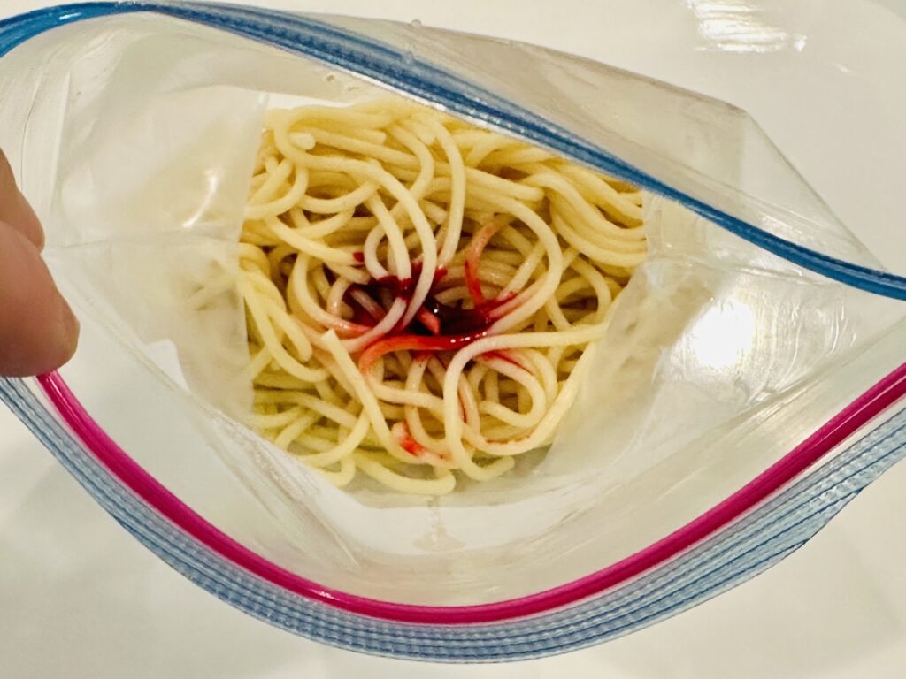 Food dye and water placed in a Ziplock bag with a portion of cooked spaghetti noodles