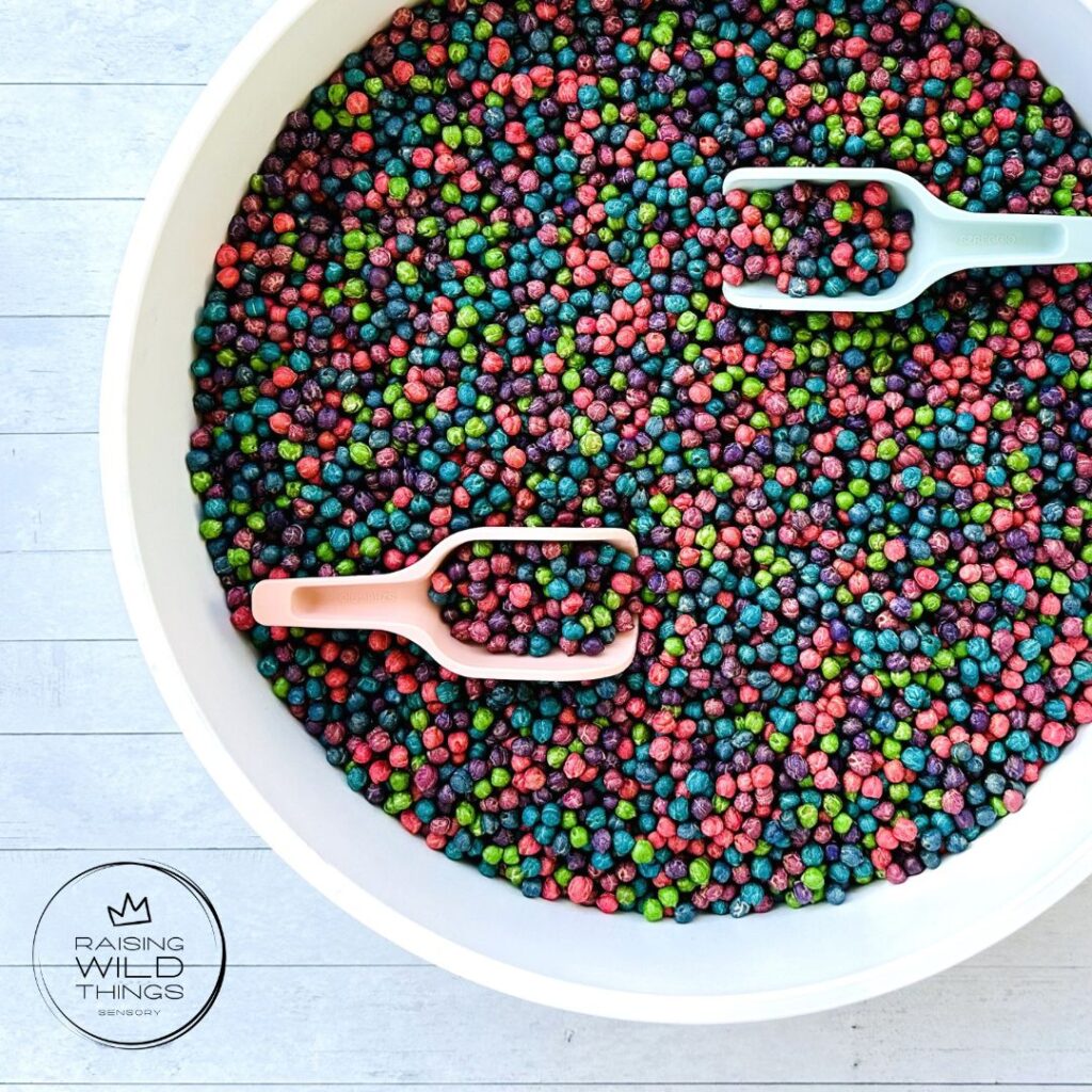 Rainbow chickpeas in a sensory bin with 2 scoops