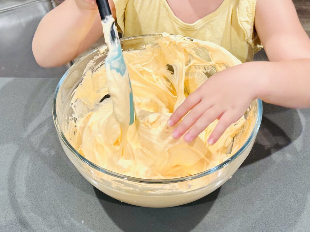 Little girl mixing fluffy pumpkin slime.