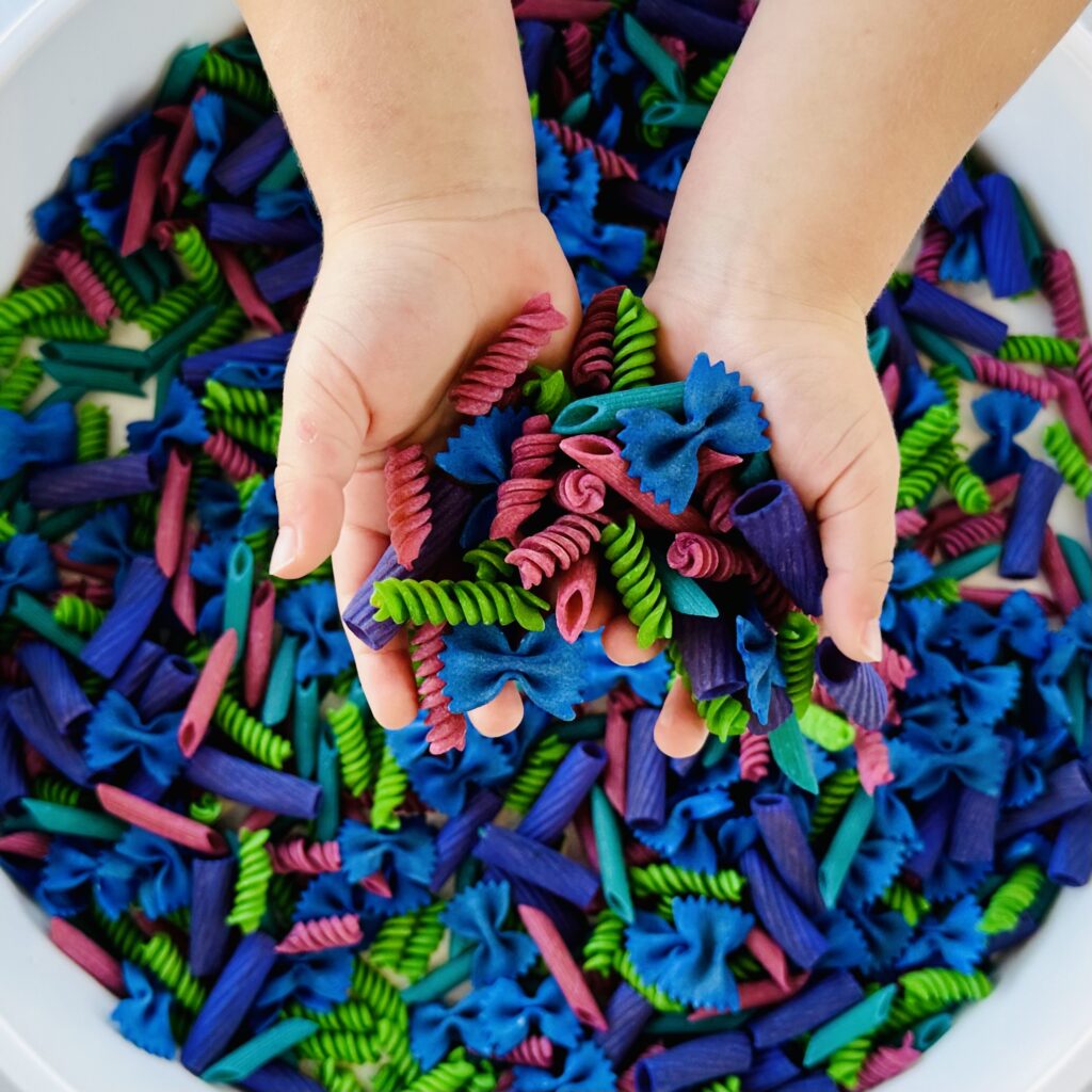 Child's hands holding colored pasta