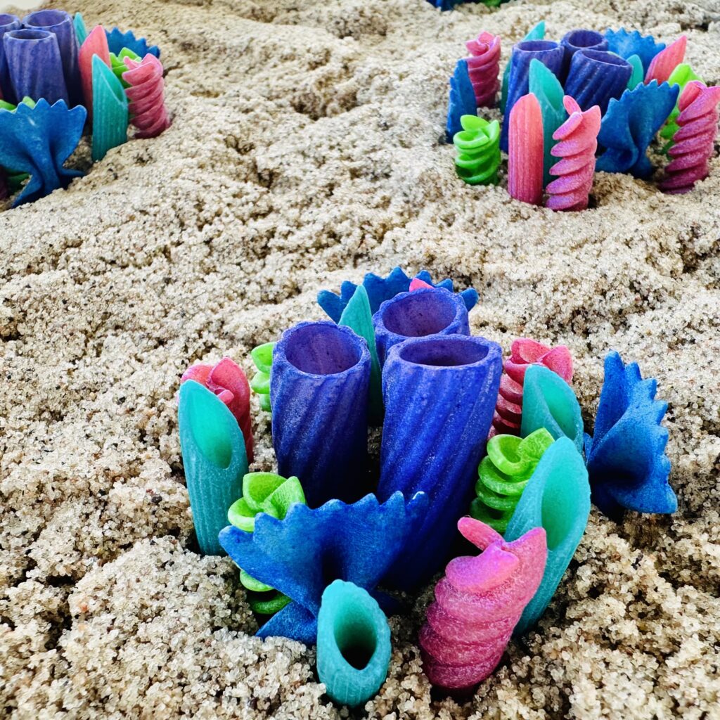 Colored pasta noodles pressed into the kinetic sand creating a coral reef