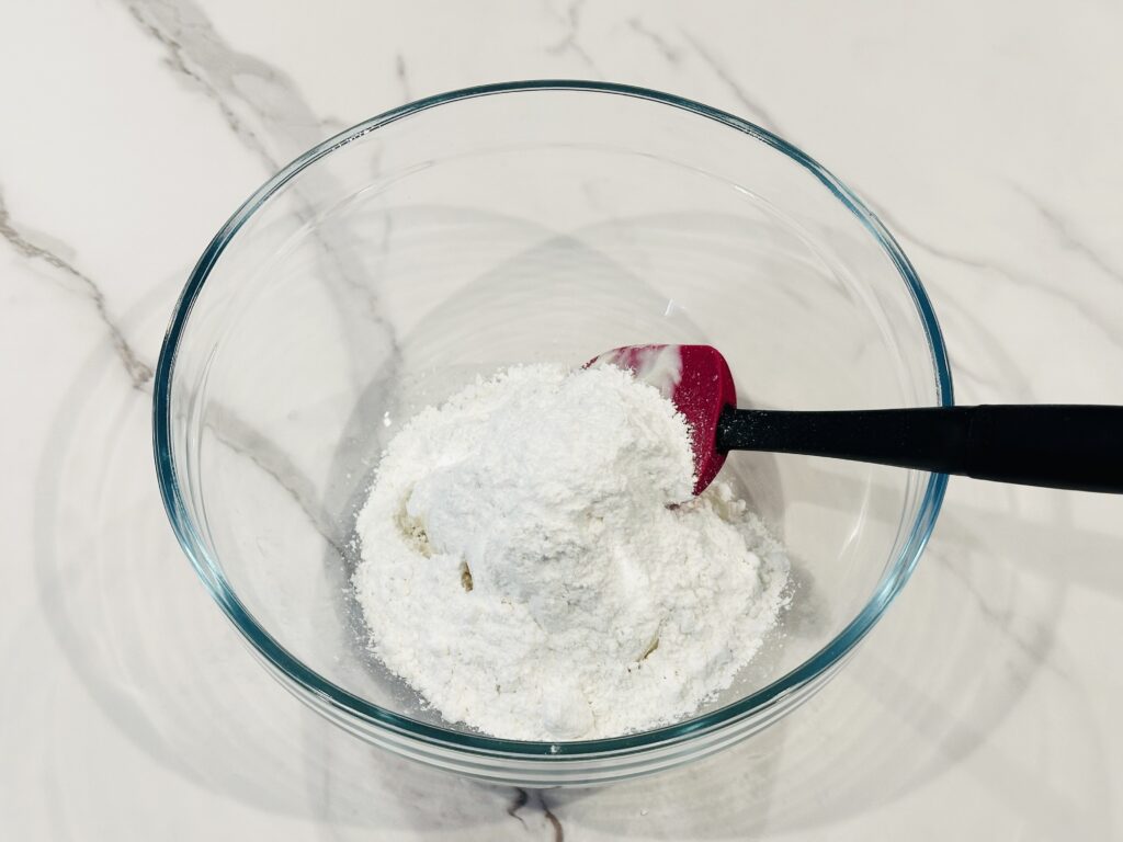 Powdered sugar added to the frosting in a mixing bowl