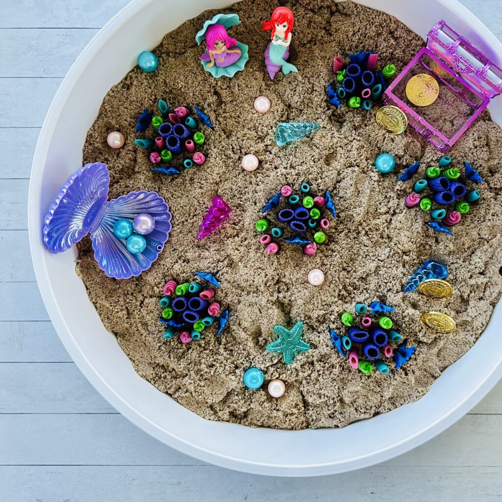 Mermaid treasures added to the sensory bin kinetic sand and coral reef