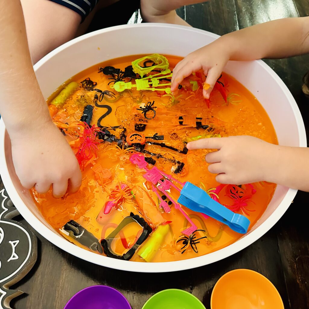 Kids digging their hands into the best Halloween Jello Sensory bin.