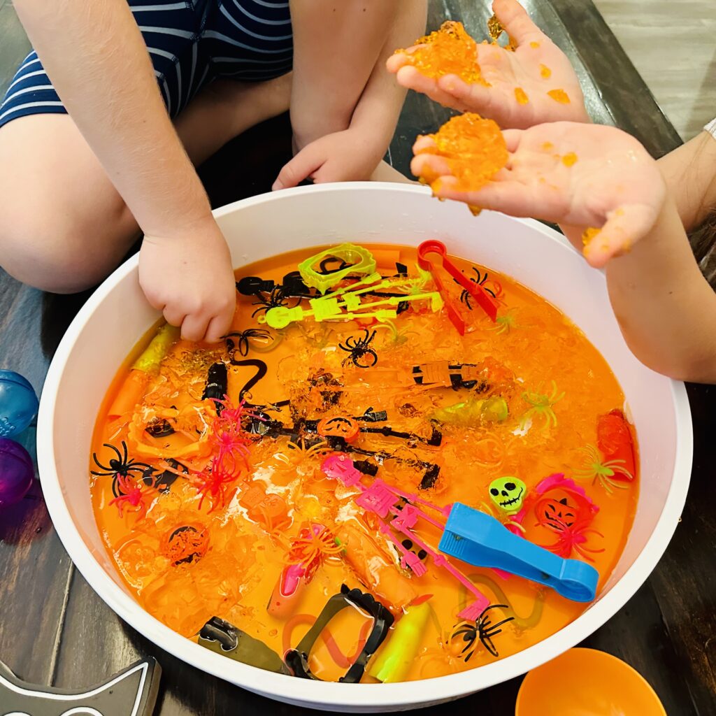 Kids digging their hands into the best Halloween Jello Sensory bin.