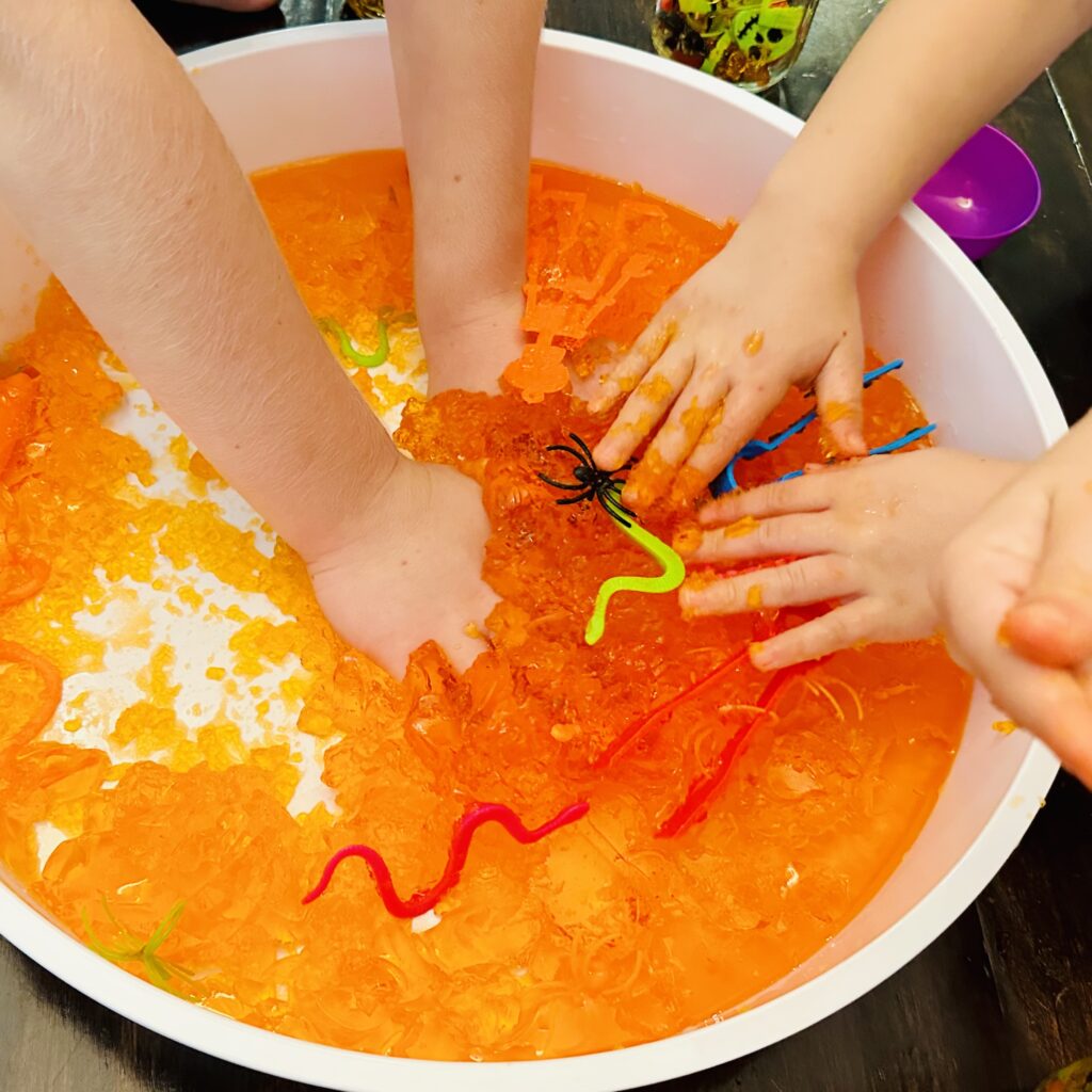 Kids digging their hands into the best Halloween Jello Sensory bin.