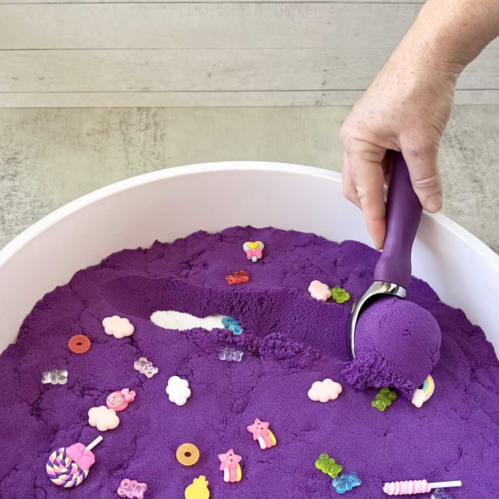 Scooping the kinetic sand with an ice cream scooper