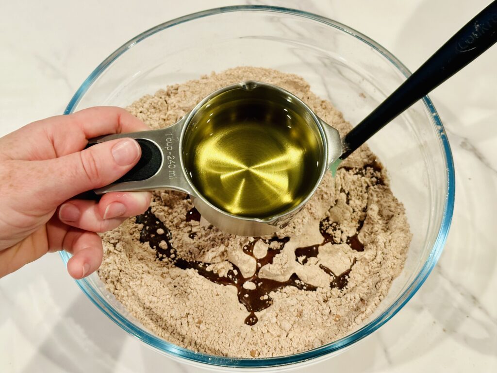 Drizzling oil over the cocoa powder and flour in a mixing bowl 