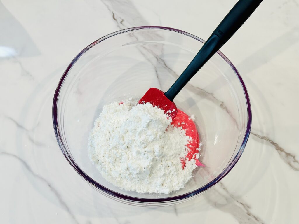 Powdered sugar added to the frosting in a mixing bowl