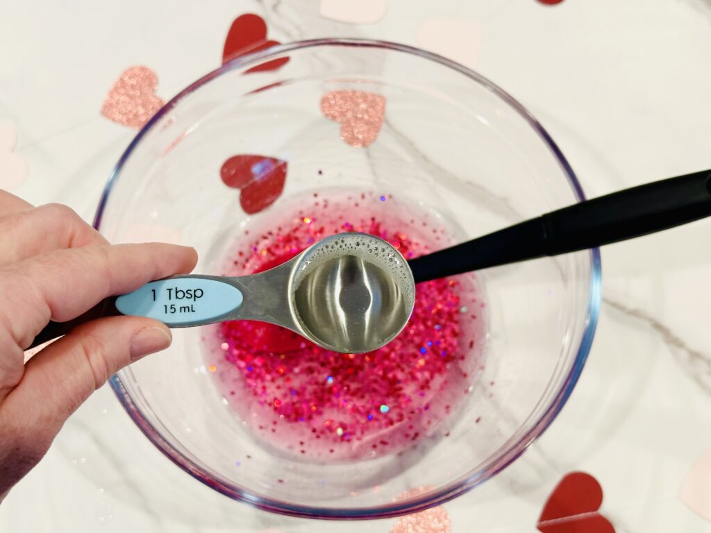 Adding contact solution to make the Glitter & Hearts Valentine's Day Slime