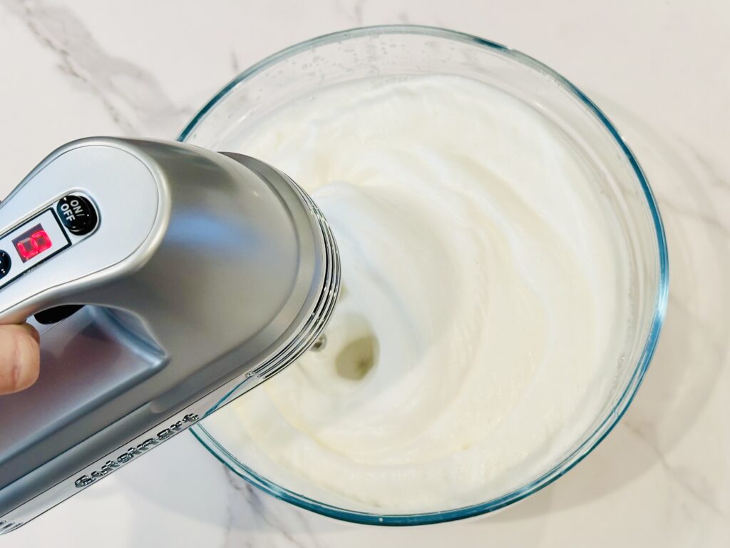 Chickpea liquid and cream of tar tar being whipped with a hand blender