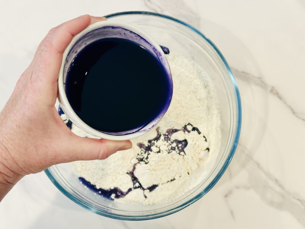 Drizzling oil over flour in a mixing bowl