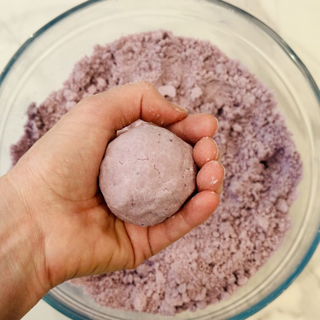 Hand making a ball of moon dough to test the consistency