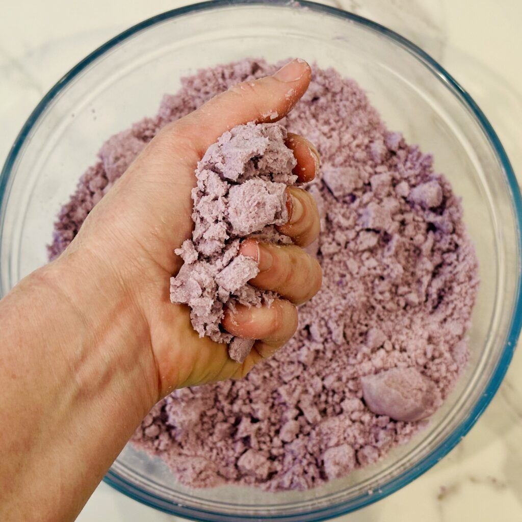 Hand squeezing the moon dough to test the consistency