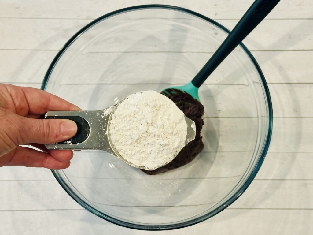 Powdered sugar added to the frosting in a mixing bowl