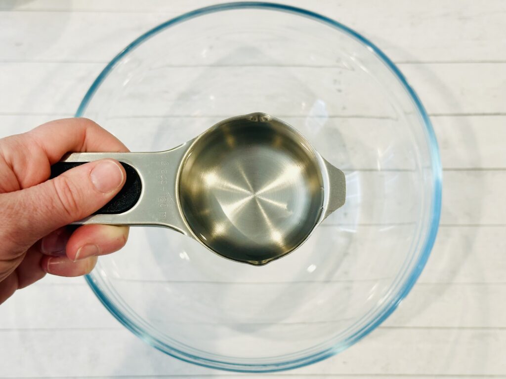 Adding 1/2 cup clear glue to a mixing bowl.