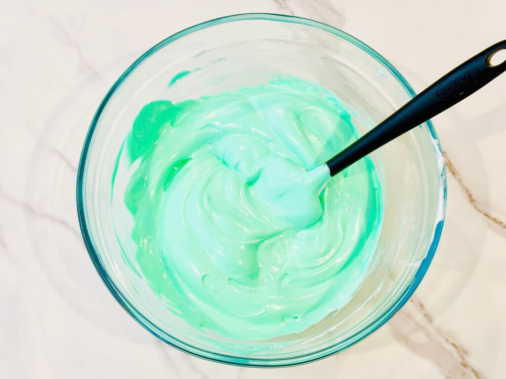 Adding food coloring to the glue, shaving foam, and baking soda mixture