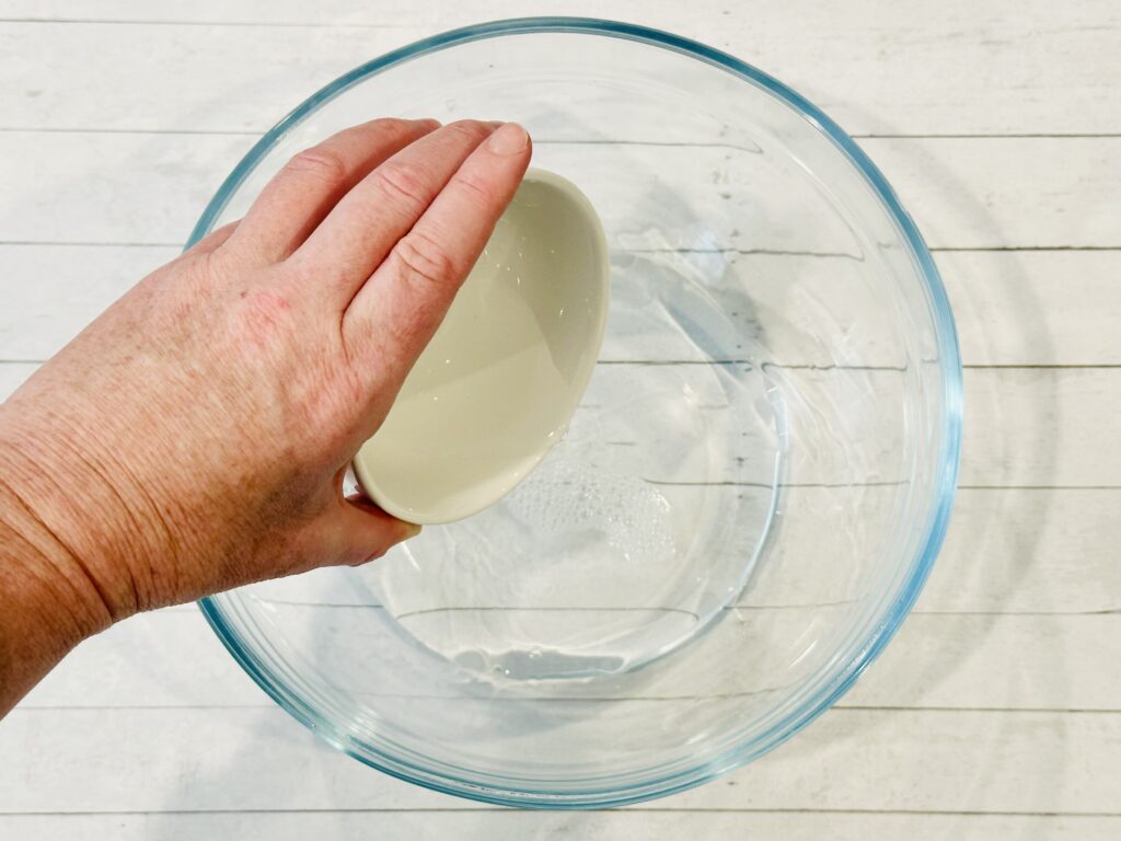 Adding water and baking soda mixture to the clear glue in the mixing bowl.