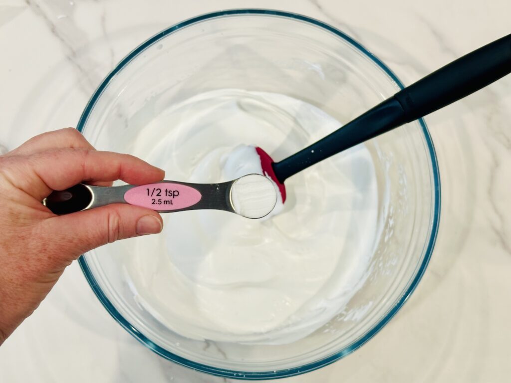 Adding baking soda to the shaving cream and glue mixture in a mixing bowl