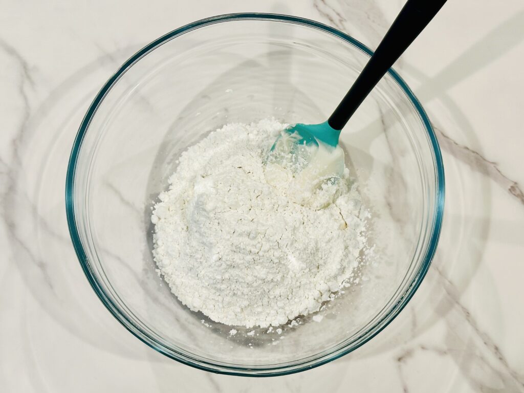 Powdered sugar added to the frosting in a mixing bowl