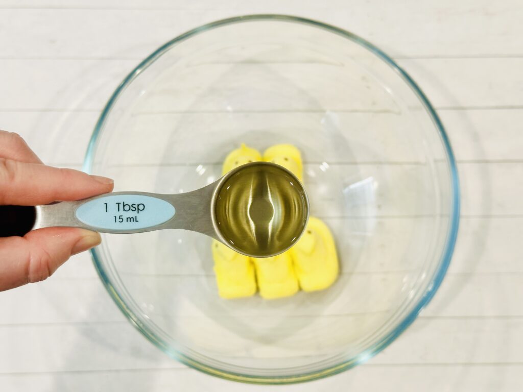 Pouring oil over the Easter Peeps in a mixing bowl