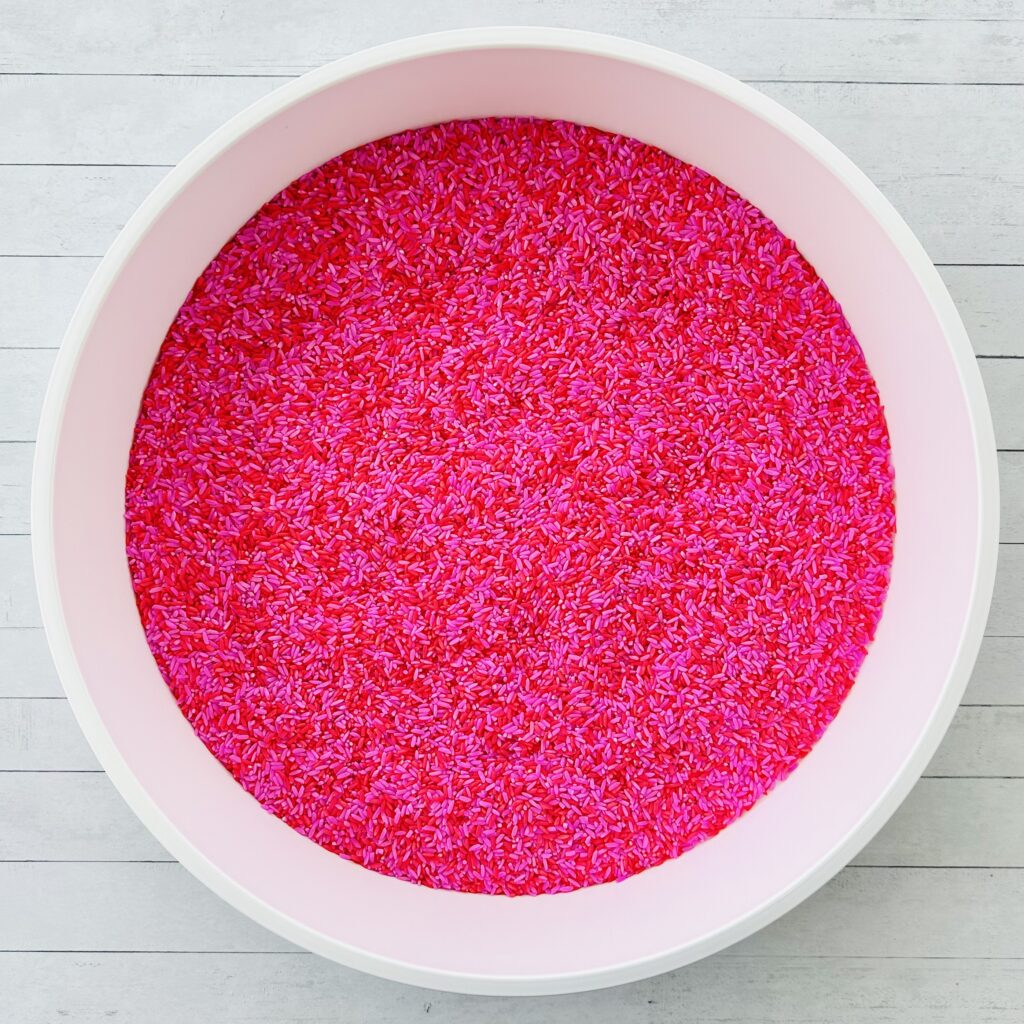 Red and pink rice in a sensory bin