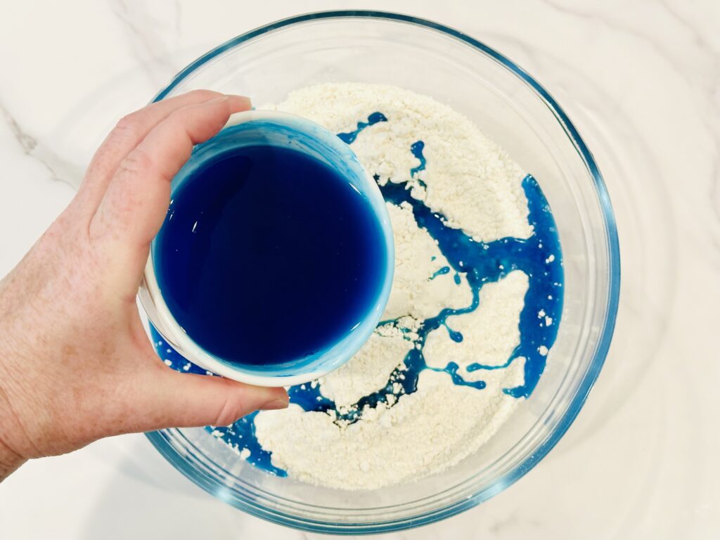 Drizzling oil over flour in a mixing bowl