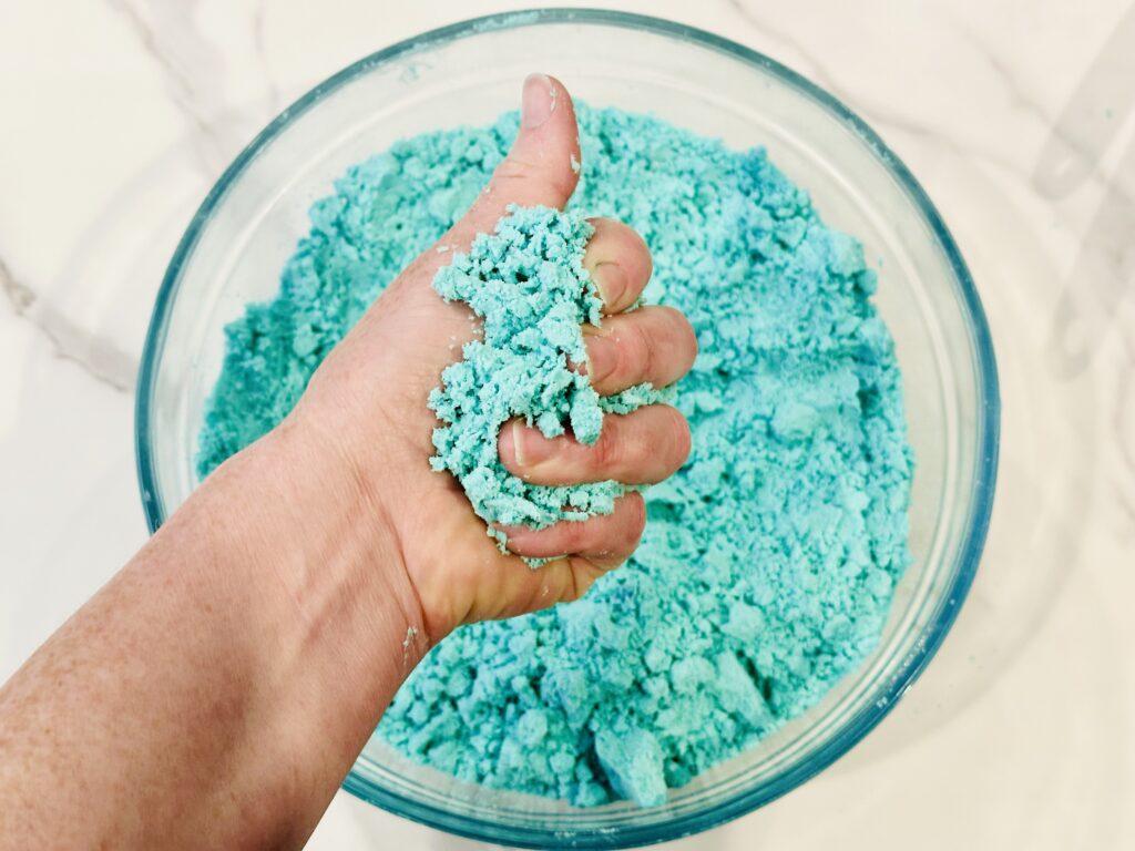 Hand squeezing the moon dough to test the consistency