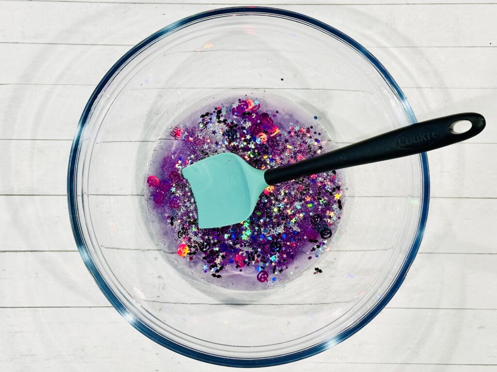 Adding glitter, confetti, and food coloring to slime mixture