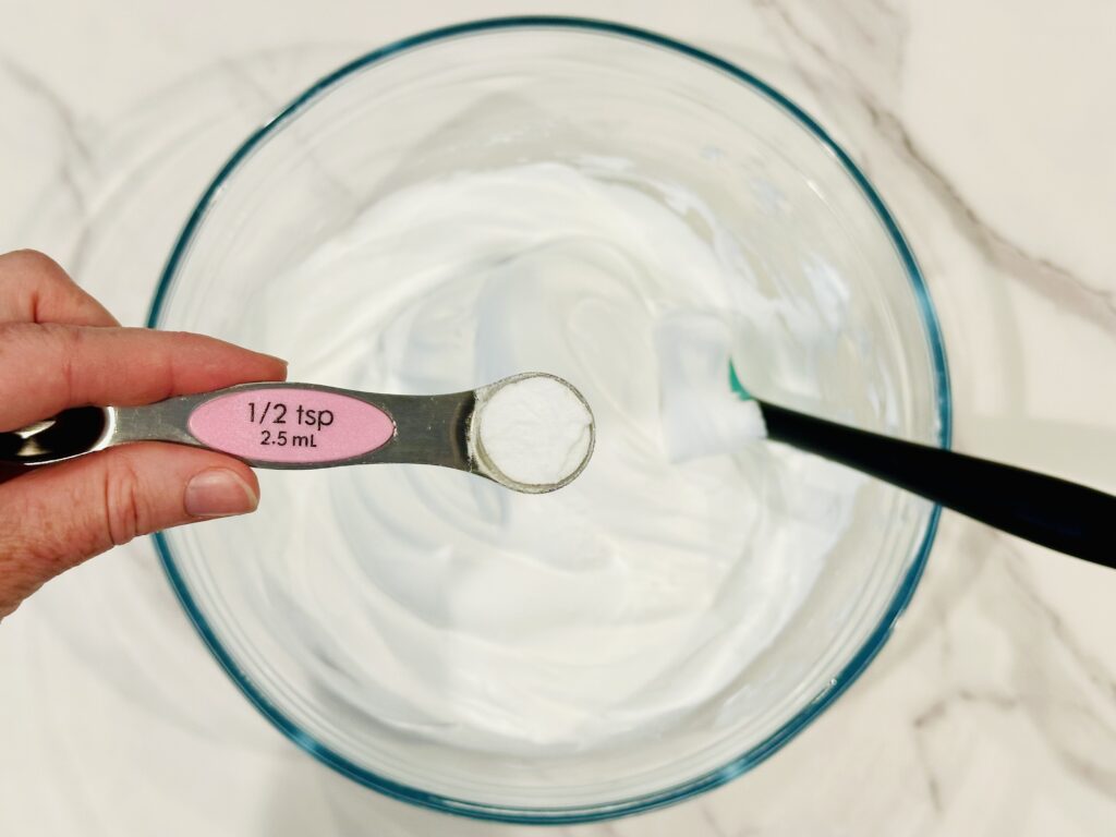 Adding baking soda to the shaving cream and glue mixture in a mixing bowl