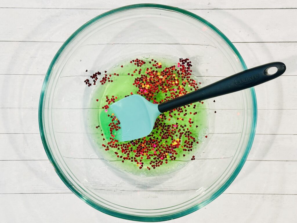 Adding glitter, confetti, and food coloring to slime mixture